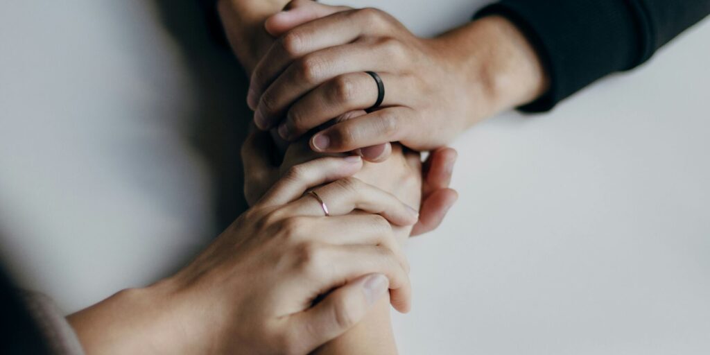 Two people holding hands in comfort and support